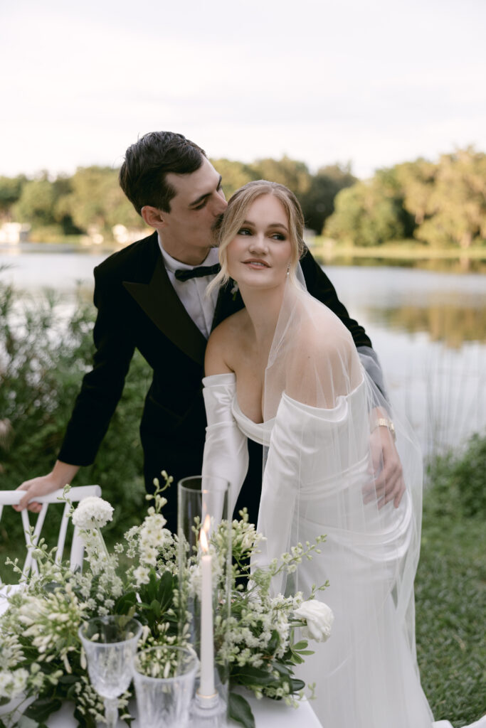 Orlando wedding makeup artist | Makeup Artist Orlando Beauty Brigade | Groom holds bride's waist while leaning on a chair