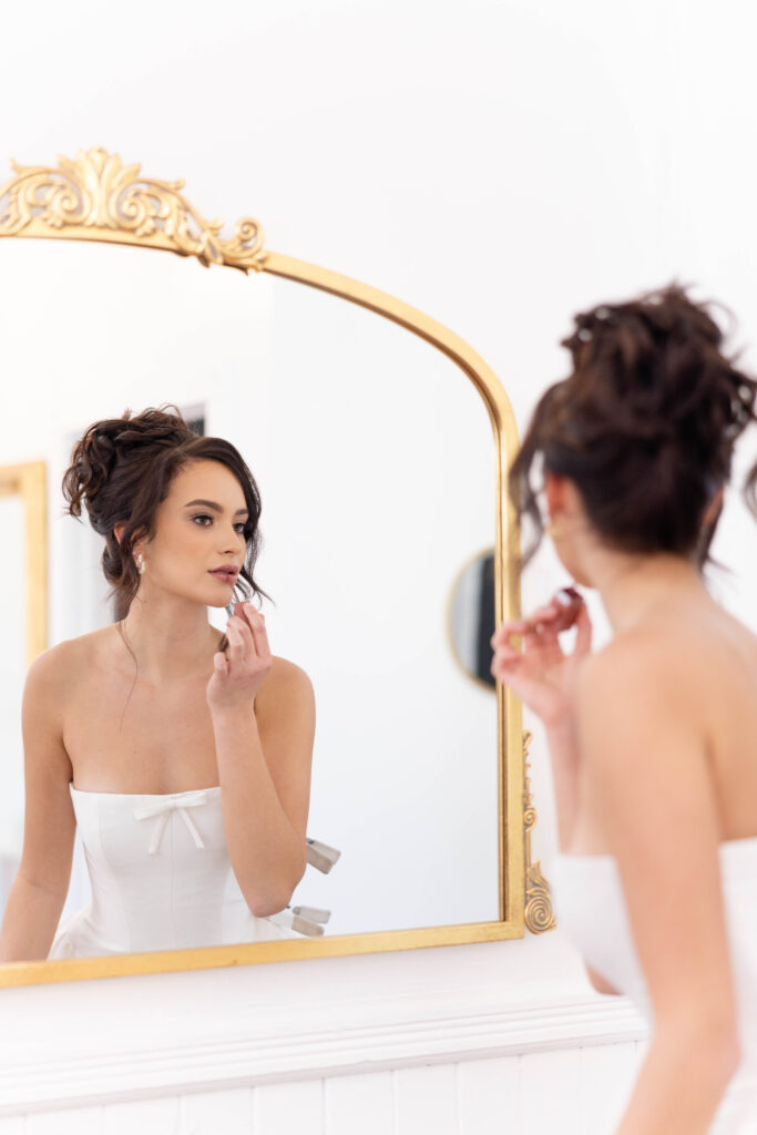 Orlando wedding hair and makeup | Makeup Artist Orlando Beauty Brigade | Bride applying lipstick facing the mirror